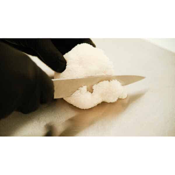 A person in black gloves slices an Australian-grown Freeze-Dried Lion's Mane Mushroom (whole or powder) with a knife on a chopping board.