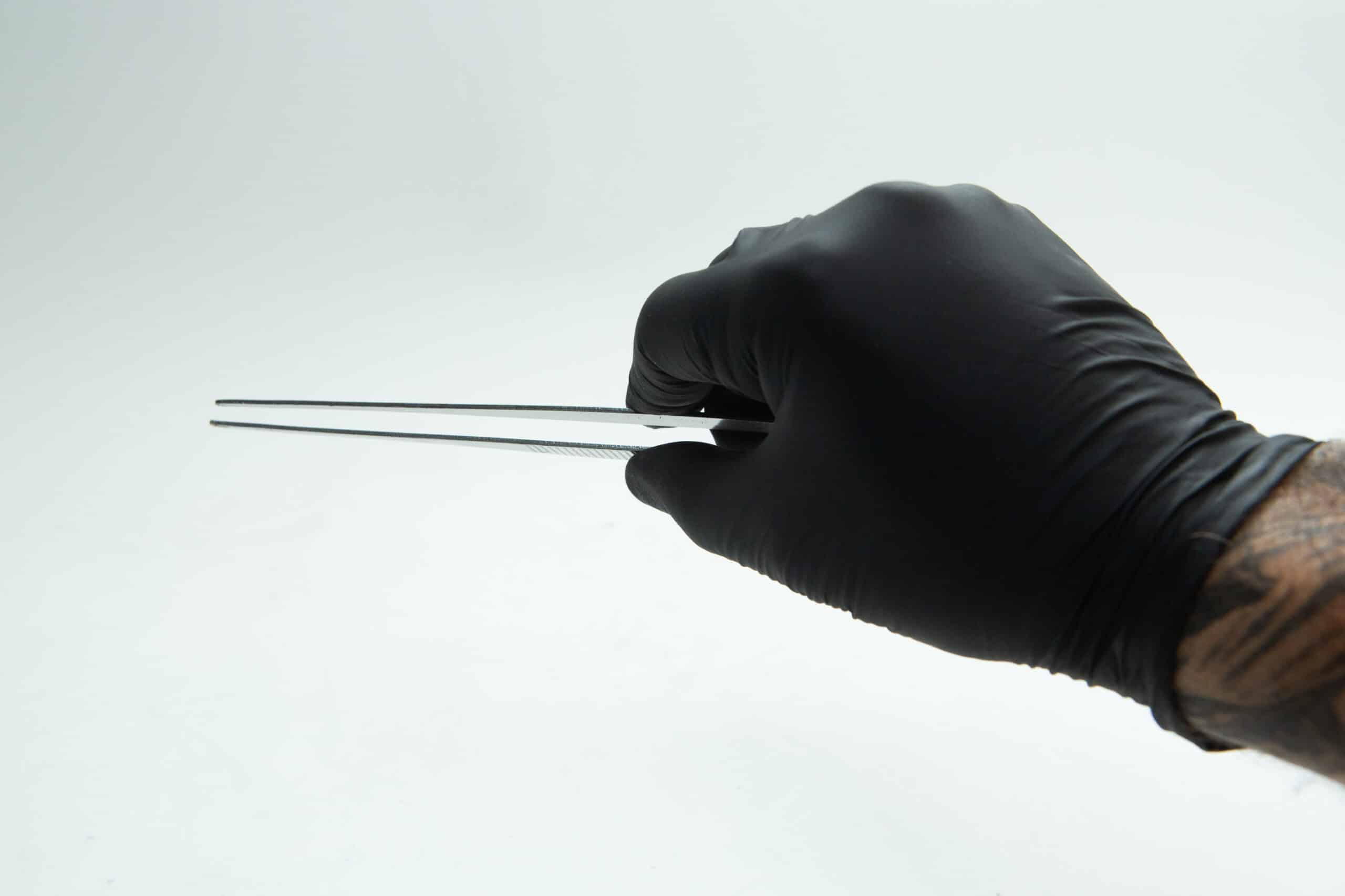 Stainless Steel Plant tissue culture Lab Forceps | Curved & Straight Tips | 25cm 8 A hand in a black glove holding metal tweezers against a white background.