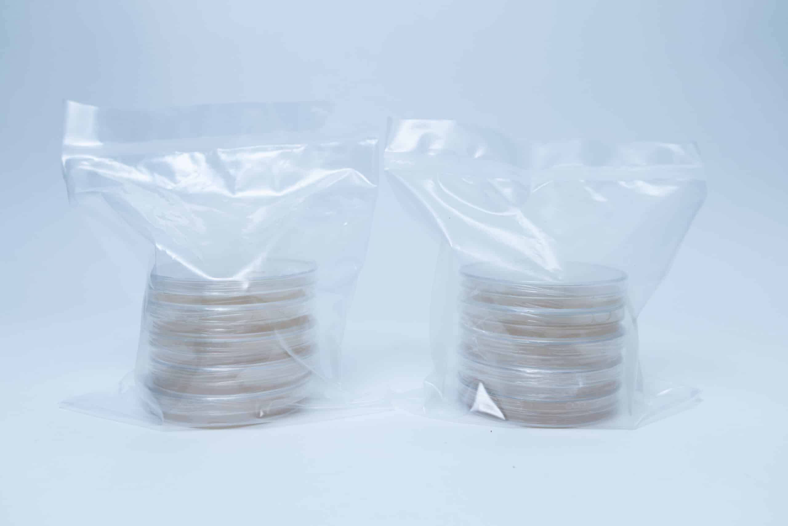 Two stacks of petri dishes are sealed separately in clear plastic bags on a white background.