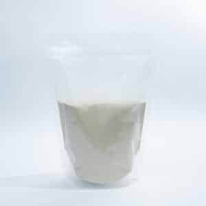A clear resealable bag filled halfway with a light beige powder, set against a white background.